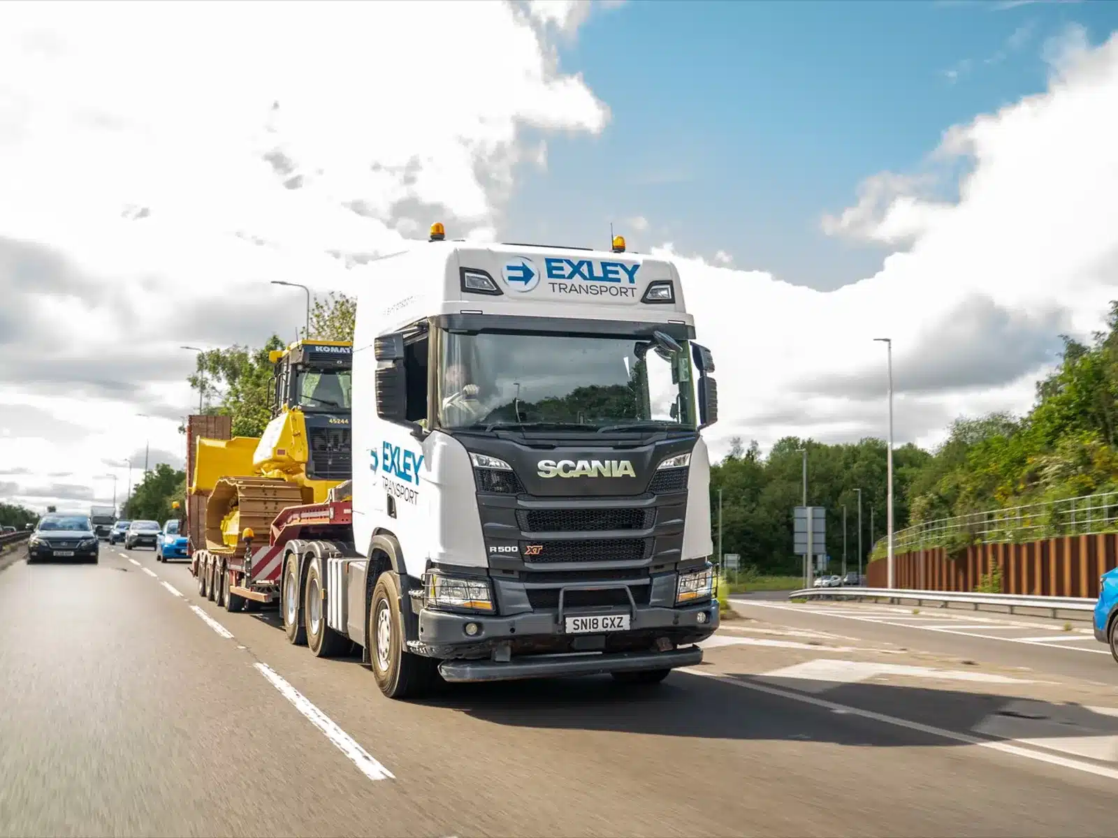 Low loader carrying plant on a dual carriageway